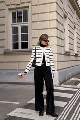 a lady in a black mock neck sweater, a striped knit top and a pair of black pants